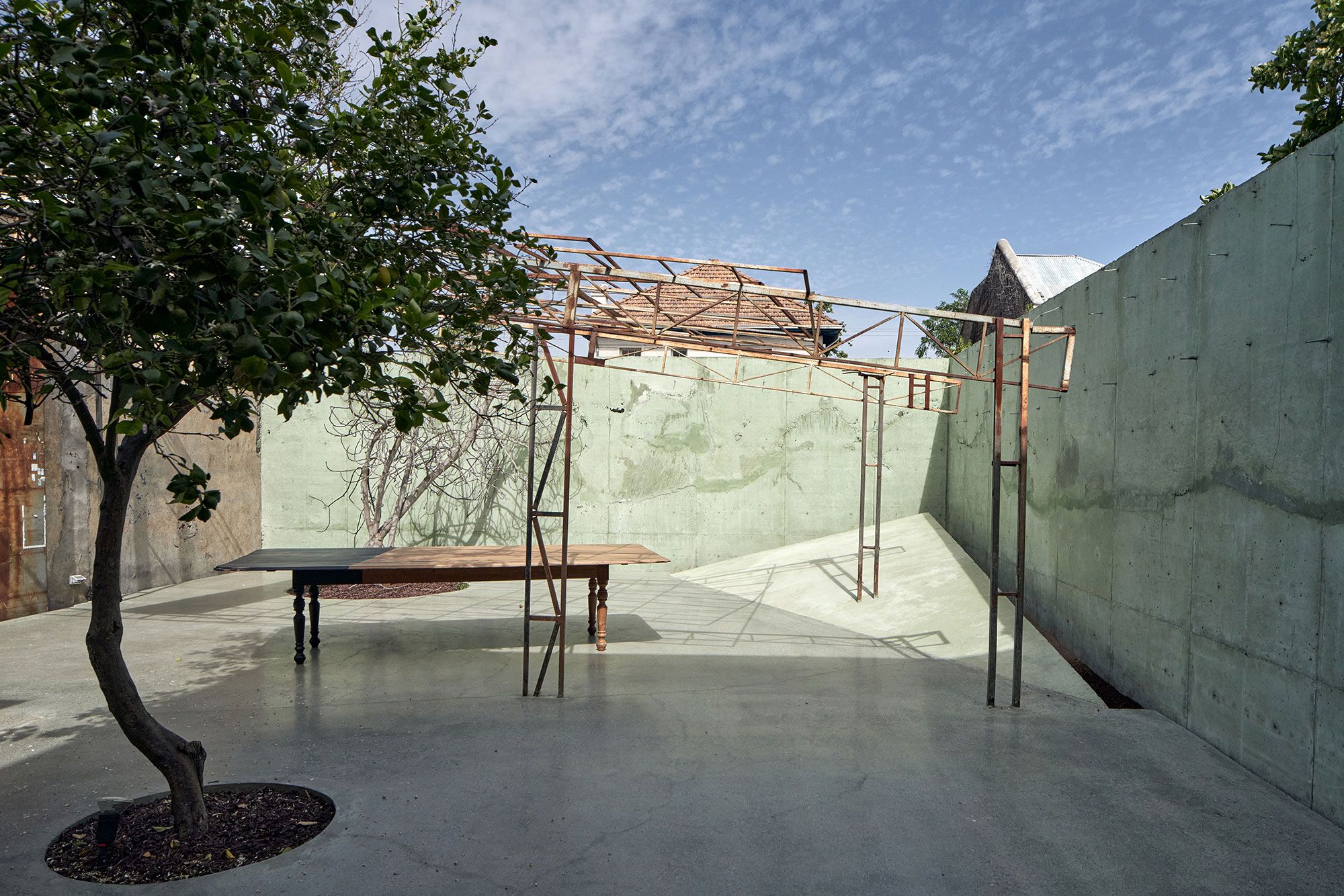 The courtyard: green concrete walls and the iron frame of the old hall.